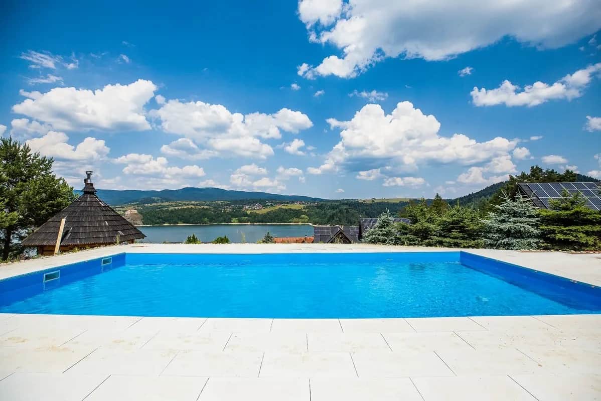 Azurblaue Poolfläche und Seepanorama unter strahlend blauem Himmel