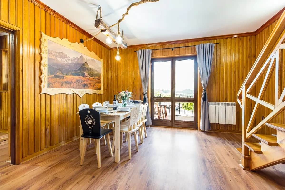 Gedeckter Esstisch in holzverkleidetem Innenraum mit Bergblick