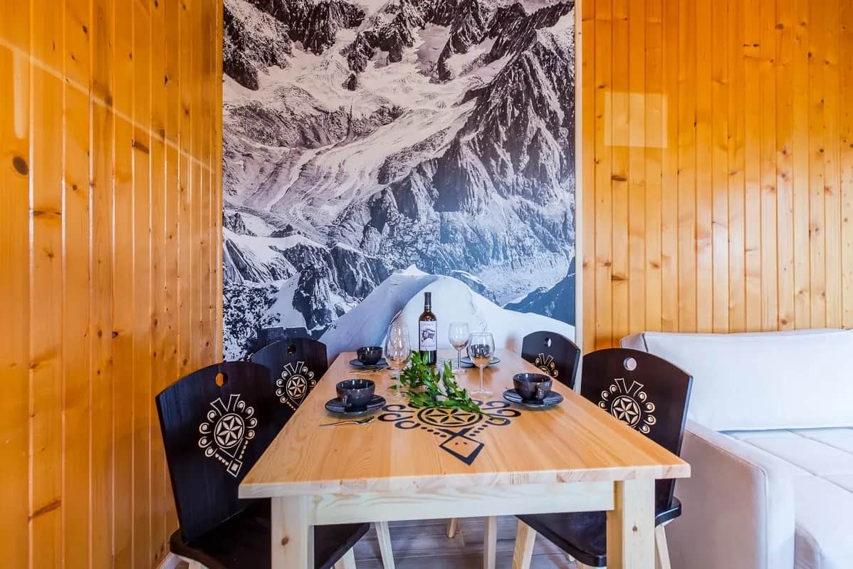 Holzesszimmer mit Tisch und Stühlen im Góralen-Stil vor Berg-Tapete