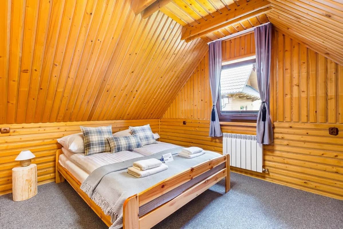 Dachgeschoss-Schlafzimmer mit Doppelbett und schrägen Holzdecken