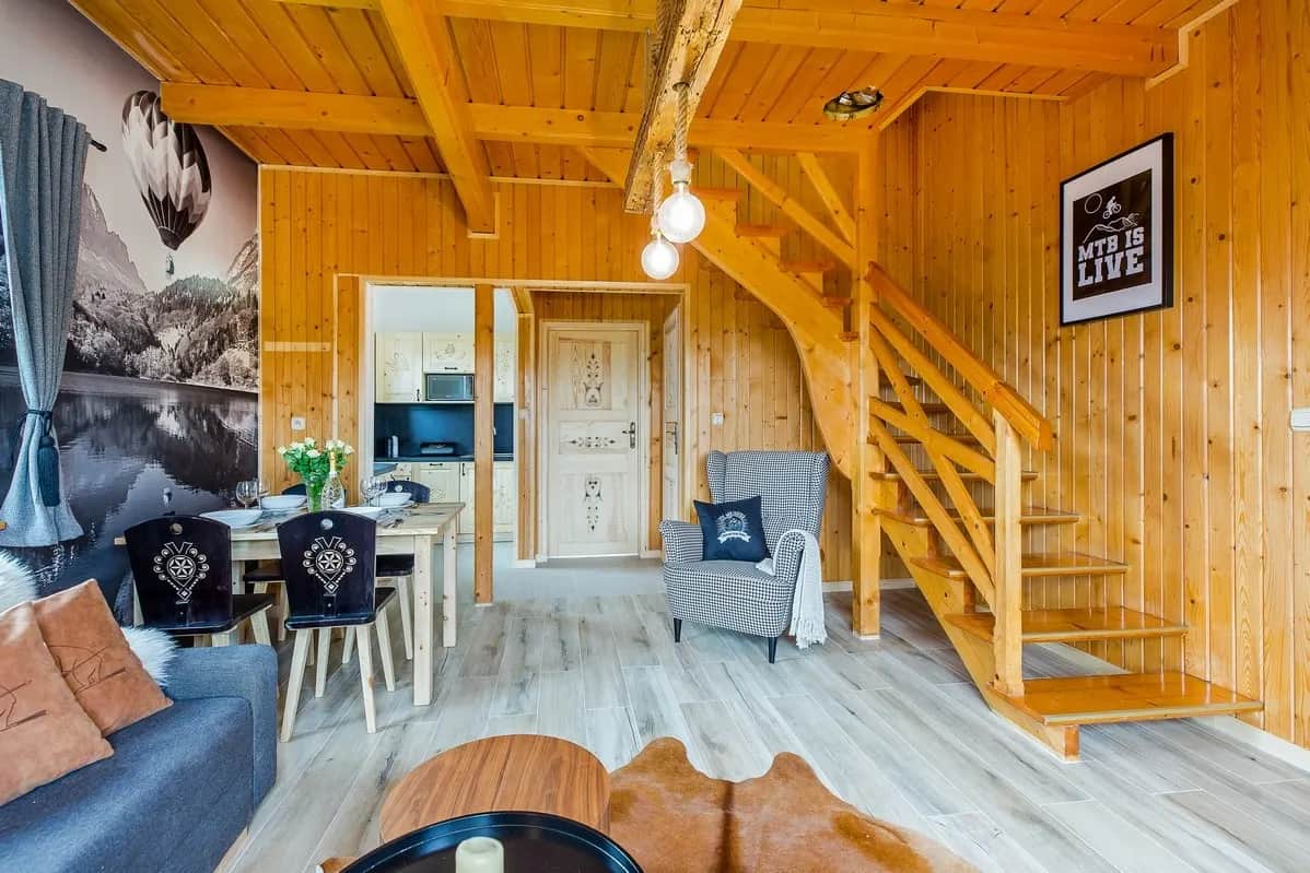 Salon z drewnianą klatką schodową i widokiem na aneks