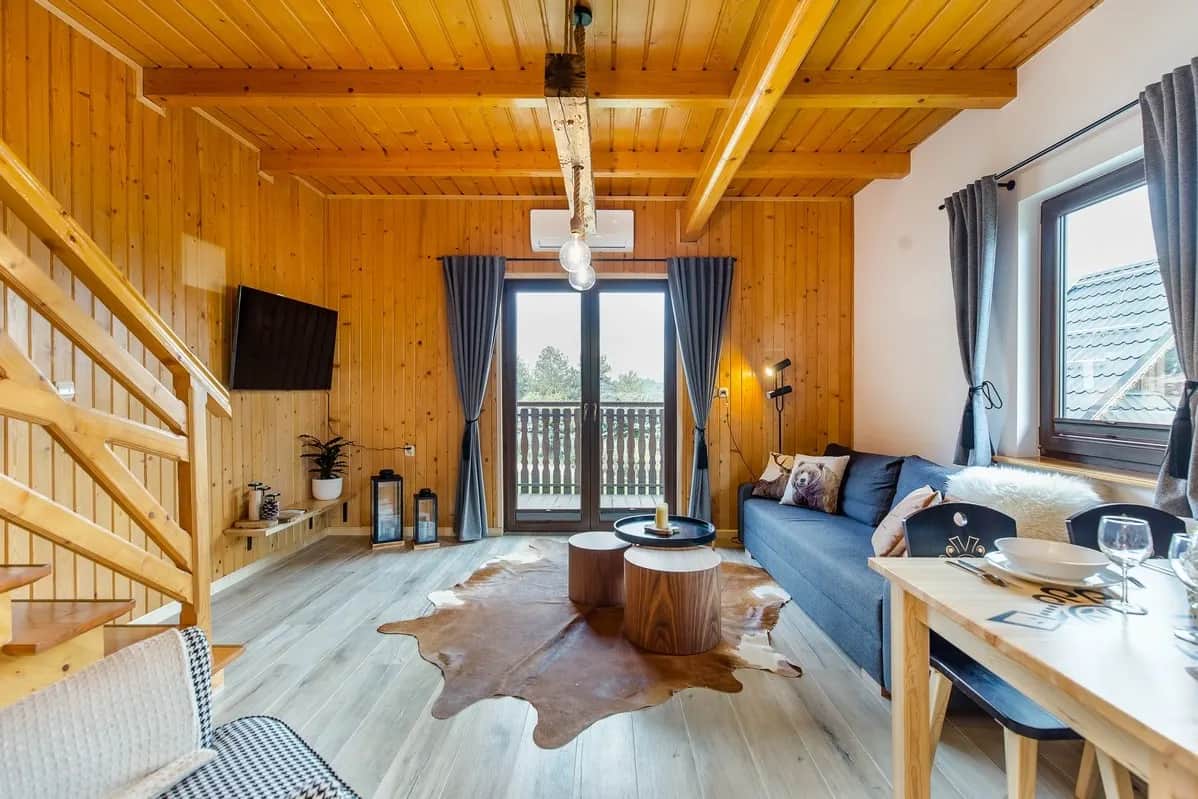 Salon z rozkładaną sofą i widokiem na balkon przez szklane drzwi