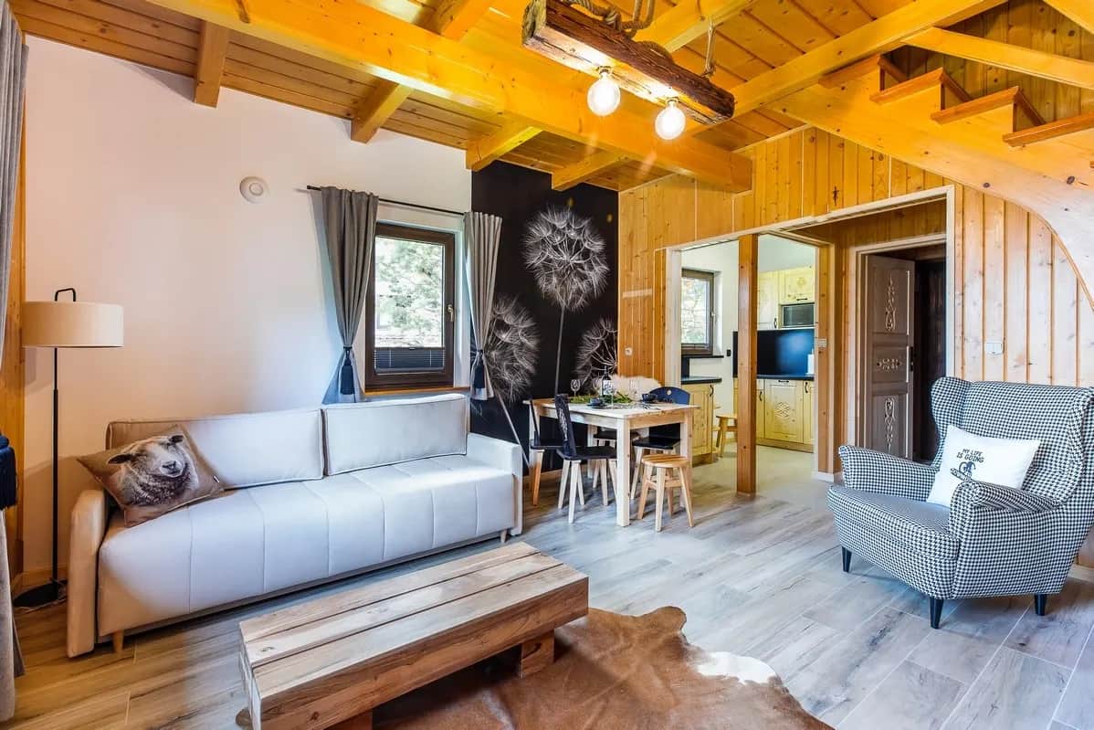 Przestronny salon z jasną kanapą, fotelem w pepitkę i jadalnią