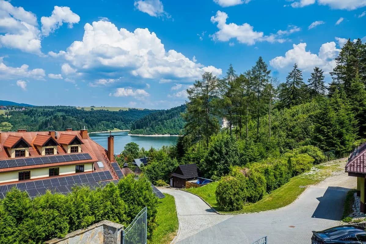 Blick auf See und bewaldete Hügel zwischen den Ferienhäusern des Resorts