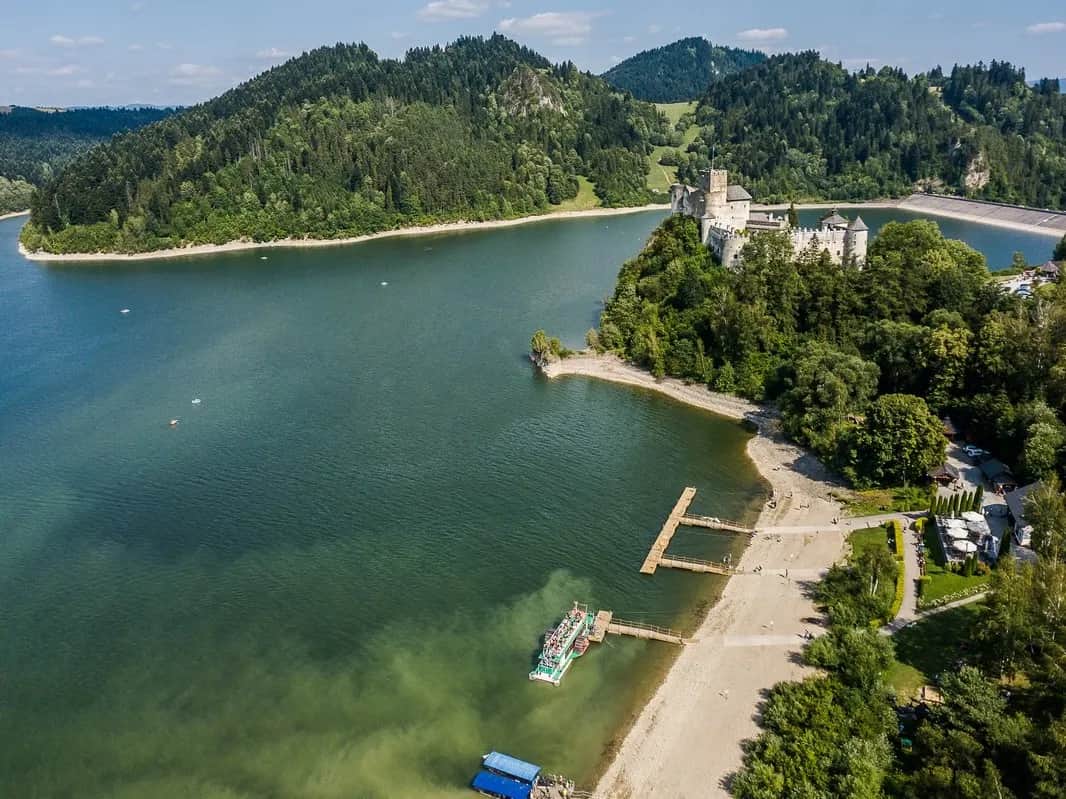 See mit Burg am Ufer und Tatra-Bergkette am Horizont