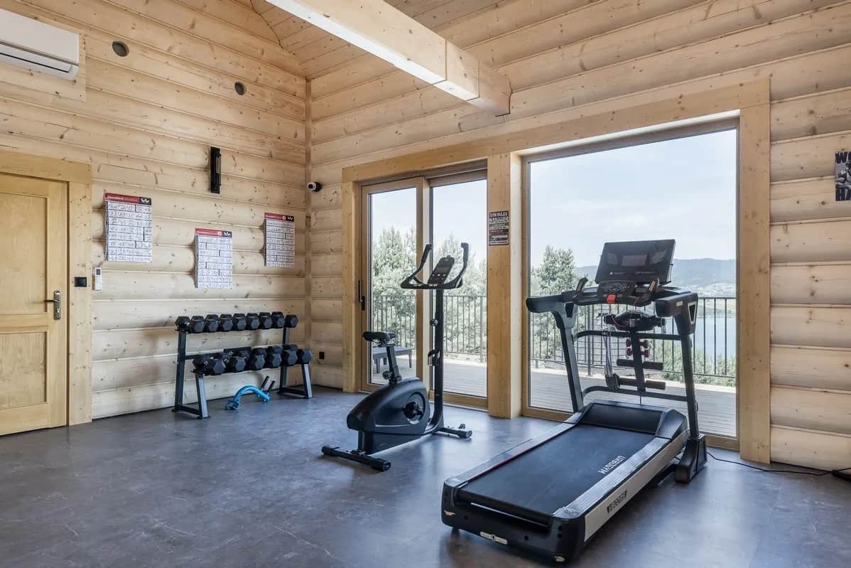 Fitnessraum mit Laufband, Heimtrainer und Hanteln am Panoramafenster