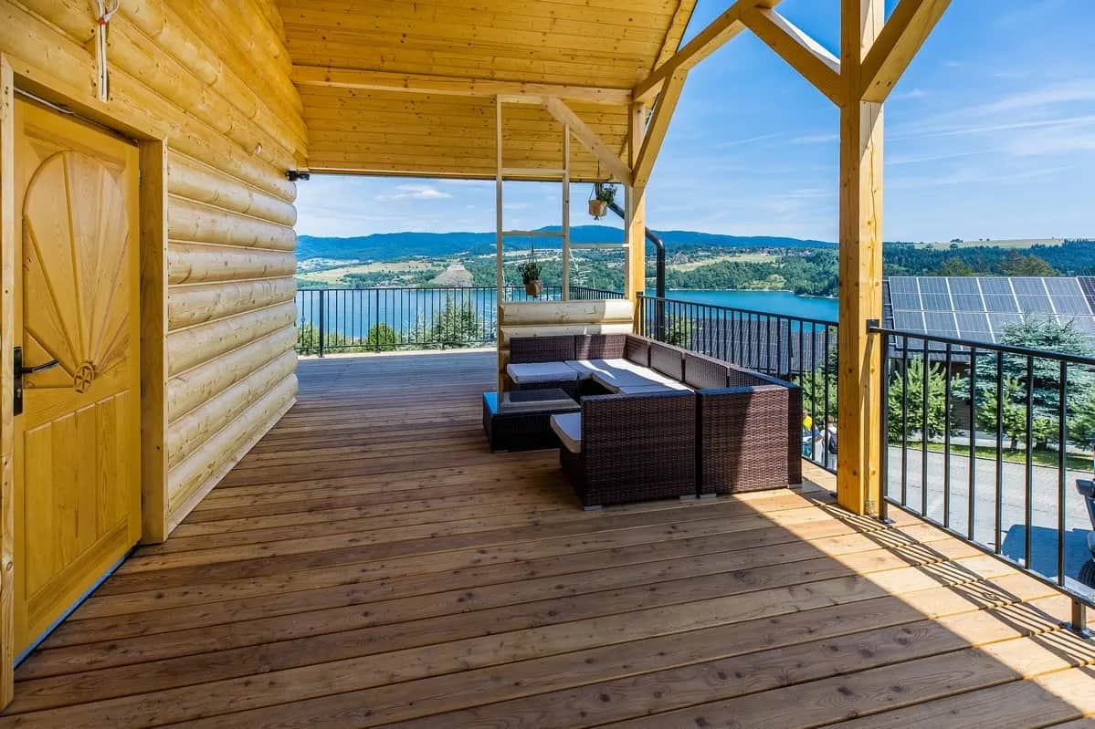 Überdachte Holzterrasse mit Loungemöbeln am See