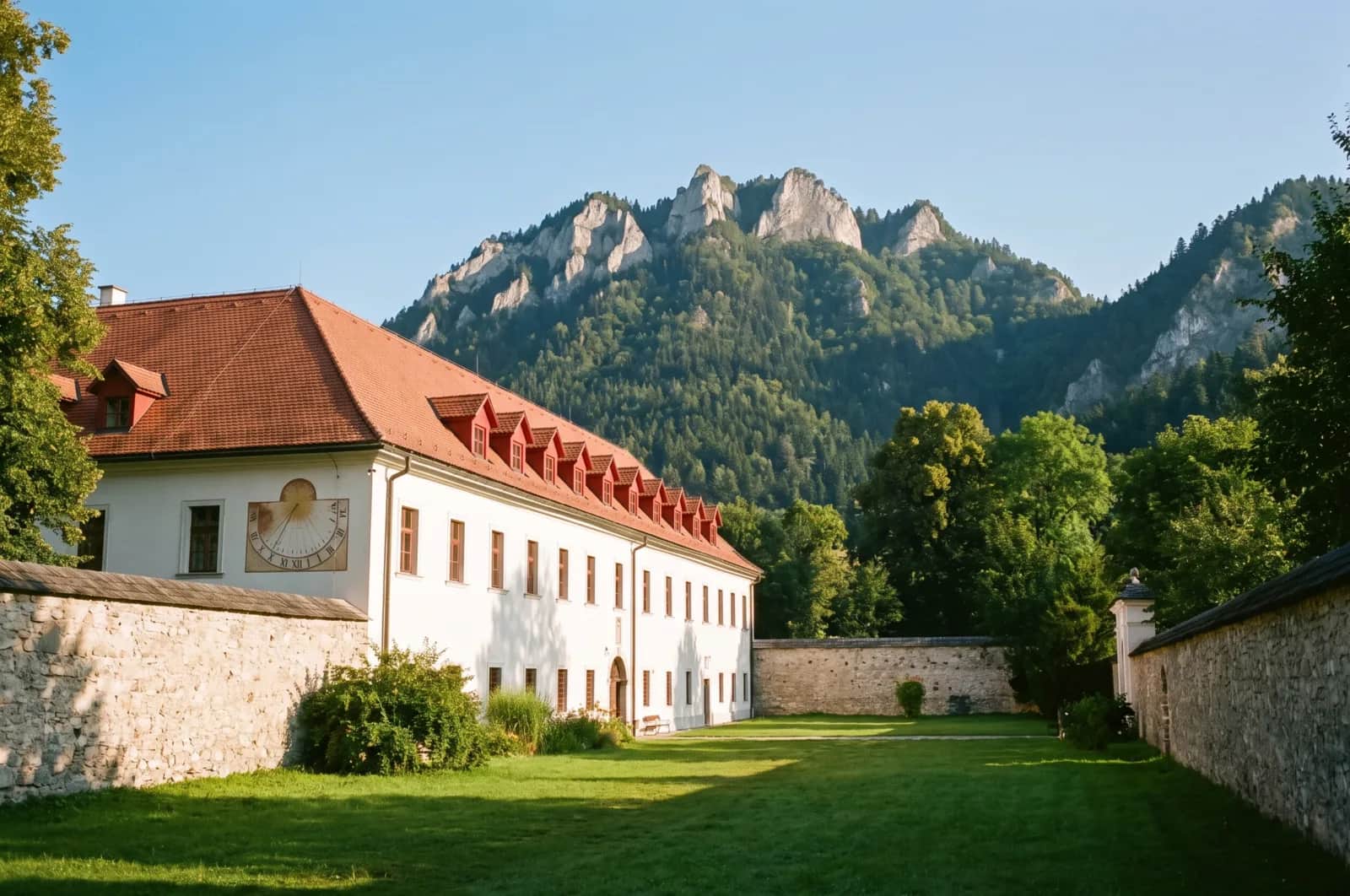 Czerwony Klasztor - średniowieczny ceglany kompleks z czerwonymi dachami nad Dunajcem, w tle skaliste turnie Trzech Koron i lesiste zbocza Pienin